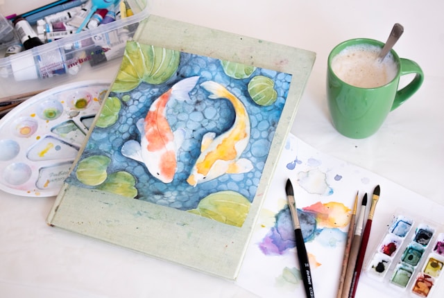 Watercolor painting set with art supplies and a cup, by Mia, age 30.